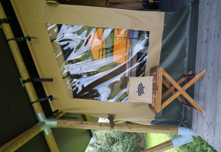 Tenda safari con servizi igienici privati al Domaine Bonneblond in Francia, sgabello di legno davanti.