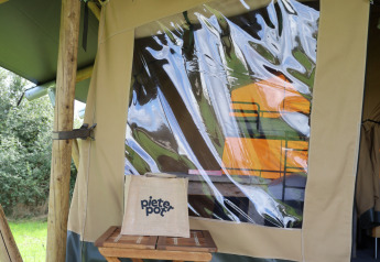 Tenda safari con servizi igienici privati al Domaine Bonneblond in Francia, sgabello di legno davanti.