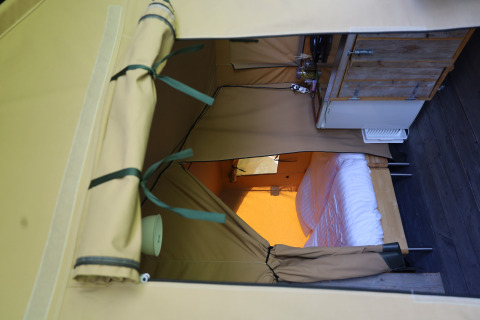 Vista interna di una tenda safari con servizi igienici privati e letto al Domaine Bonneblond, Francia.