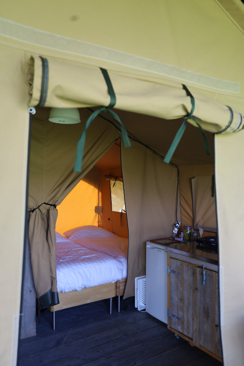 Interieur van een safaritent met eigen sanitair en bed op Domaine Bonneblond in Frankrijk.
