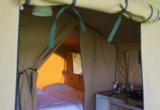 Interior view of a safari tent with private sanitary facilities and bed at Domaine Bonneblond, France.
