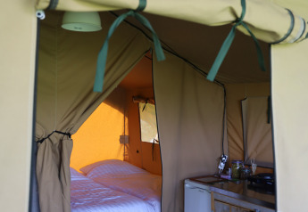 Interior view of a safari tent with private sanitary facilities and bed at Domaine Bonneblond, France.