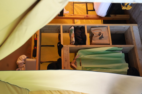 Interior of a safari tent at Domaine Bonneblond in France, showing storage shelves and hanging clothes.