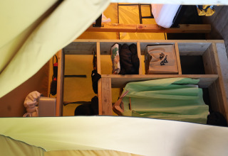 Interior of a safari tent at Domaine Bonneblond in France, showing storage shelves and hanging clothes.