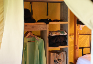 Interieur van een safaritent bij Domaine Bonneblond in Frankrijk met kleding en opbergvakken.