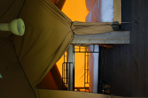 Interior view of a safari tent with bed and private bathroom at Domaine Bonneblond in France.