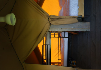 Interior view of a safari tent with bed and private bathroom at Domaine Bonneblond in France.