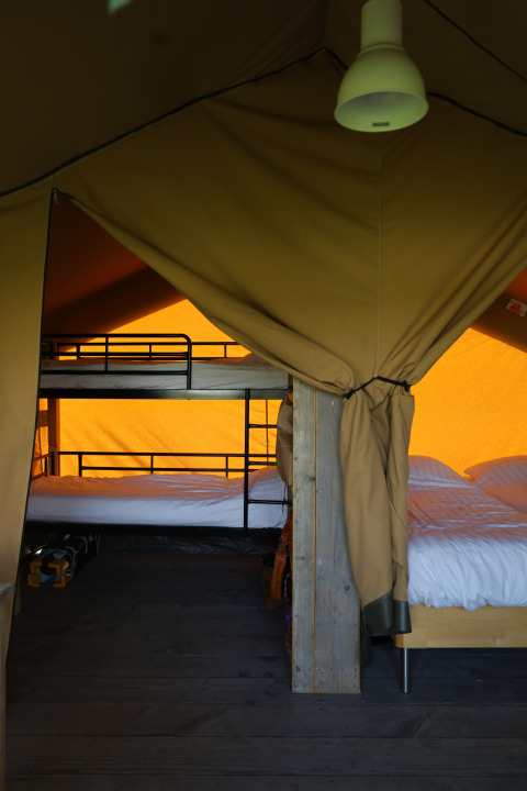 Binnenaanzicht van safaritent met bed en eigen sanitair bij Domaine Bonneblond in Frankrijk.
