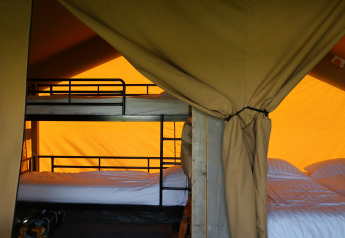 Interior view of a safari tent with bed and private bathroom at Domaine Bonneblond in France.