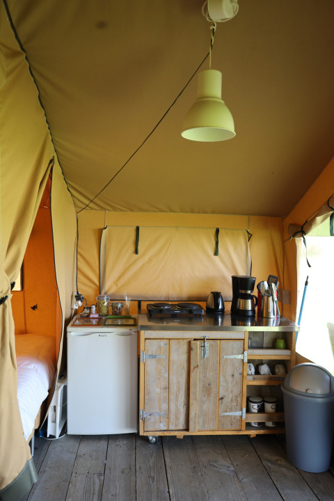 Kitchen area inside a safari tent with private sanitary facilities at Domaine Bonneblond, France.