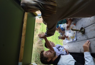 Family plays a board game together at a wooden table in a safari tent at Domaine Bonneblond, France.