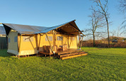 Sunny view of Glampingtent Lina, a safari tent at Glamping Franse Peer in the Netherlands with deck and chairs.