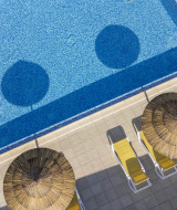 Vista aérea de piscina azul, tumbonas amarillas y sombrillas de paja en Flower Camping La Davière Plage.