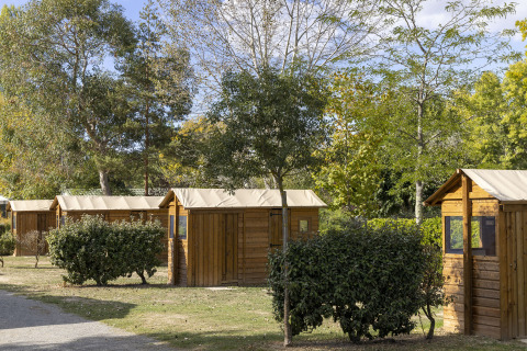 Cabañas de madera en Flower Camping La Davière Plage, rodeadas de vegetación en Pays de la Loire, Francia.