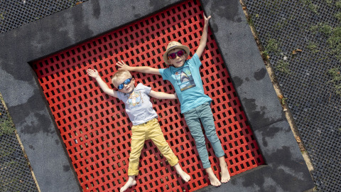 Dos niños descansan sobre una cama elástica roja en Flower Camping La Davière Plage, Pays de la Loire, Francia.