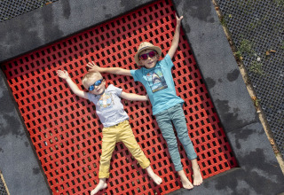Twee kinderen liggen op een rood springveld bij Flower Camping La Davière Plage in Pays de la Loire, Frankrijk.
