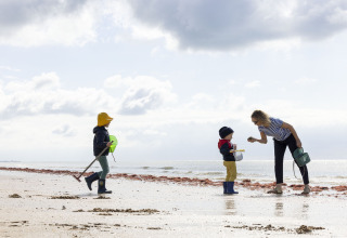 Une femme et deux enfants jouent sur la plage du Flower Camping La Davière Plage en Pays de la Loire, France.
