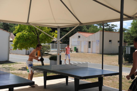 Due persone giocano a ping pong all’aperto sotto un tendone a Flower Camping La Davière Plage in Francia.