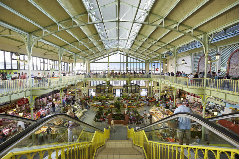Mercado cubierto de dos niveles con puestos de comida y flores en Flower Camping La Davière Plage, Francia.