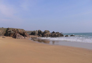 Strand med klipper og hav nær Saint Jean de Monts, Pays de la Loire, Frankrig, under en blå himmel.