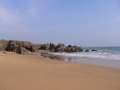 Spiaggia sabbiosa con scogli vicino a Saint Jean de Monts, Pays de la Loire, Francia, sotto cielo sereno.