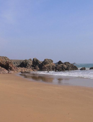 Playa rocosa y mar tranquilo cerca de Saint Jean de Monts, Pays de la Loire, Francia, bajo cielo claro.
