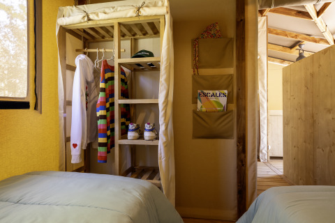 Zona de dormitorio en la tienda safari Hut Cotton Confort en Flower Camping La Davière Plage, Francia.