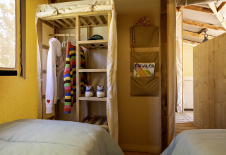 Zona de dormitorio en la tienda safari Hut Cotton Confort en Flower Camping La Davière Plage, Francia.