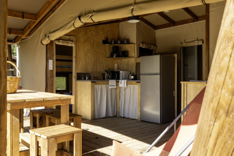 Interior de la tienda safari Hut Cotton Confort con cocina y comedor en Flower Camping La Davière Plage.