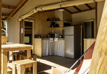 Interieur van de safaritent Hut Cotton Confort met keuken en eetruimte op Flower Camping La Davière Plage.