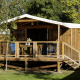 CosyFlower Confort safaritent met houten veranda, zitmeubilair en omringd door groene natuur.