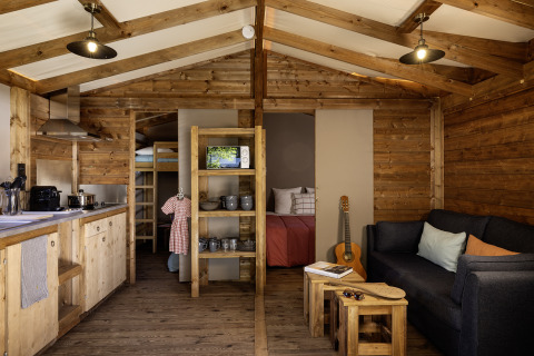 Innenraumaufnahme eines CosyFlower Confort Safari-Zelts mit Holzmöbeln bei Flower Camping La Davière Plage.
