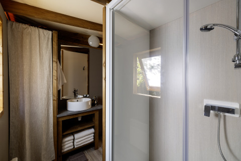 Badezimmer im CosyFlower Confort Safarizelt auf Flower Camping La Davière Plage in Frankreich, mit Dusche und Waschbecken.
