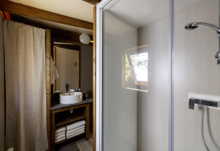 Bagno nella tenda safari CosyFlower Confort a Flower Camping La Davière Plage, Francia, con doccia e lavandino.