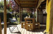 Houten terras van safaritent Hut Cotton Confort op Flower Camping La Davière Plage in Frankrijk, met zitplaatsen.