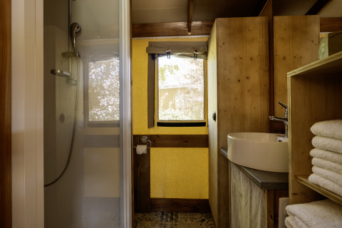 Baño dentro de la tienda safari Hut Cotton Confort en Flower Camping La Davière Plage, con ducha moderna.