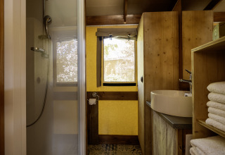 Baño dentro de la tienda safari Hut Cotton Confort en Flower Camping La Davière Plage, con ducha moderna.