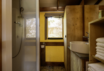 Baño dentro de la tienda safari Hut Cotton Confort en Flower Camping La Davière Plage, con ducha moderna.