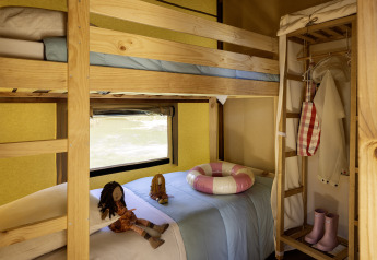 Dormitorio infantil dentro de la tienda safari Hut Cotton Confort en Flower Camping La Davière Plage, Francia.