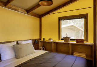 Gezellige slaapkamer in een safaritent bij Hut Cotton Confort, Flower Camping La Davière Plage, Frankrijk.