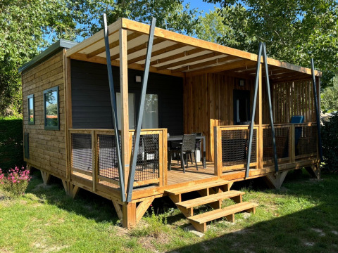 Photo du chalet Cottage Cannelle avec extérieur en bois et grande terrasse dans un environnement verdoyant.