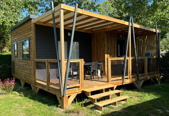 Photo du chalet Cottage Cannelle avec extérieur en bois et grande terrasse dans un environnement verdoyant.