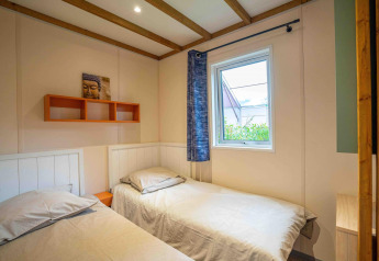 Camera con due letti singoli, finestra e arte Buddha al Cottage Cannelle, Flower Camping La Davière Plage, Francia.