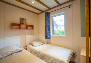 Dormitorio con dos camas individuales, ventana y arte de Buda en Cottage Cannelle, Flower Camping La Davière Plage, Francia.