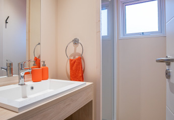 Bagno moderno al Cottage Cannelle, Flower Camping La Davière Plage, con tocchi arancioni e mobile in legno.