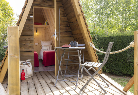 Knusse Cabadienne-hut met houten terras, tafel, stoelen en twee eenpersoonsbedden binnen.