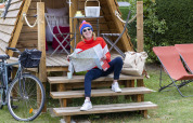 Mujer con mapa sentada en las escaleras de una cabaña Cabadienne en Flower Camping La Davière Plage, Francia.