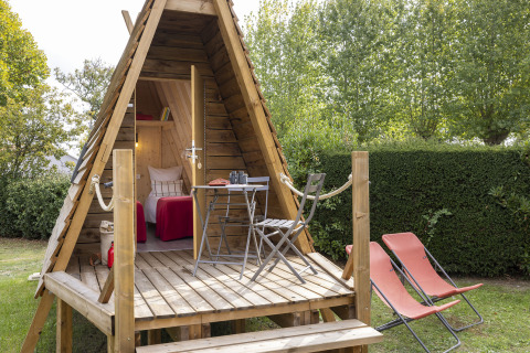 Knusse Cabadienne-hut op Flower Camping La Davière Plage in Frankrijk met houten terras en stoelen.