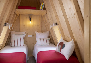 Vista interior de dos camas individuales en una cabaña de madera Cabadienne en Flower Camping La Davière Plage.