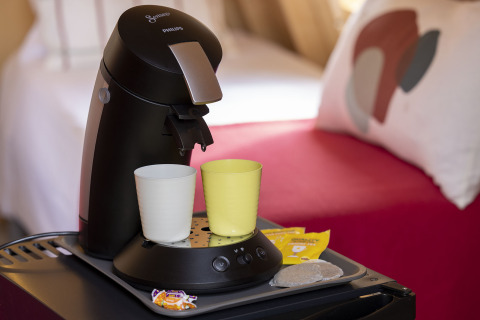 Cafetera con dos tazas y suministros sobre una mesa en una cabaña de Flower Camping La Davière Plage, Francia.